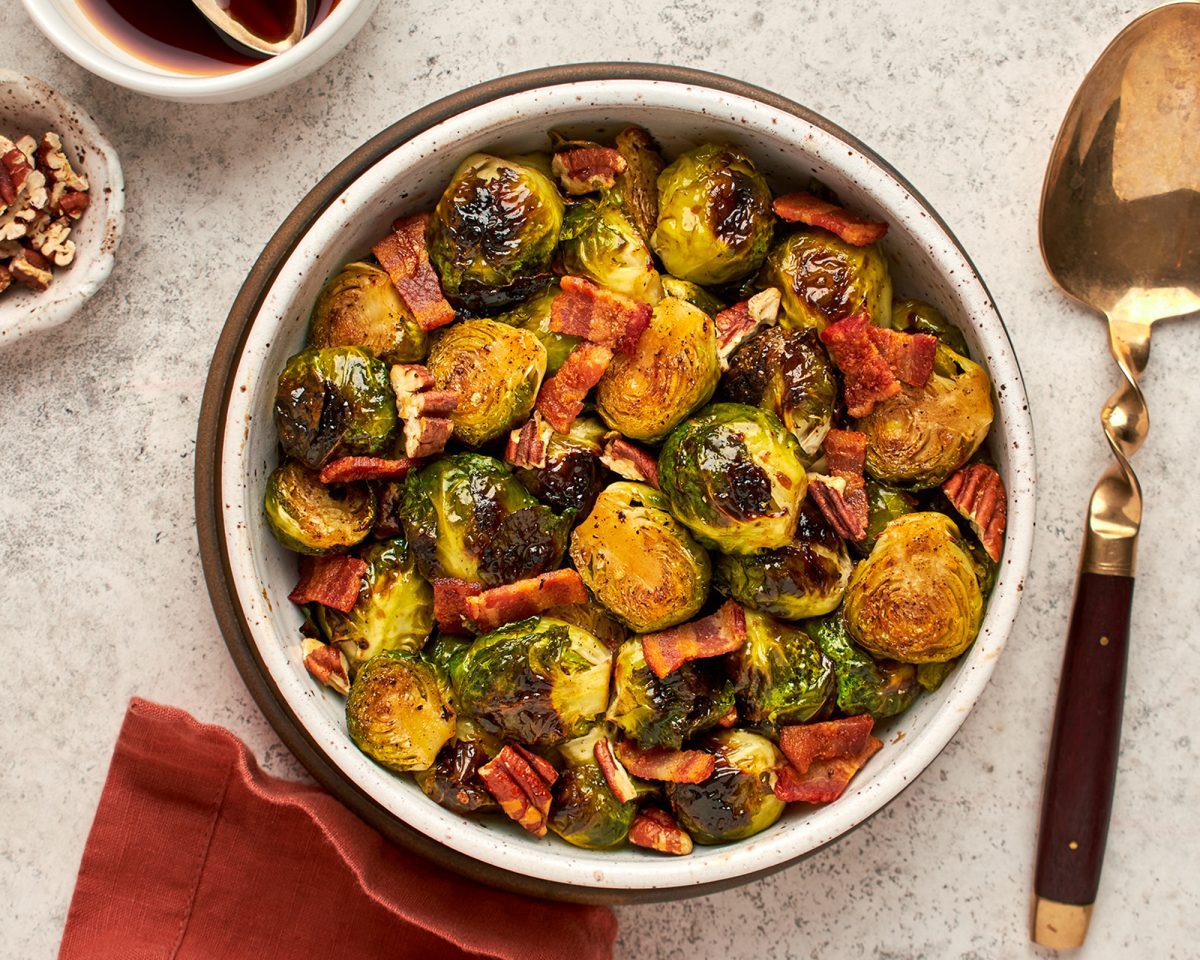 roasted Brussels sprouts with bacon in bowl with serving spoon and linen napkin