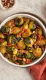 roasted Brussels sprouts with bacon in bowl with serving spoon and linen napkin