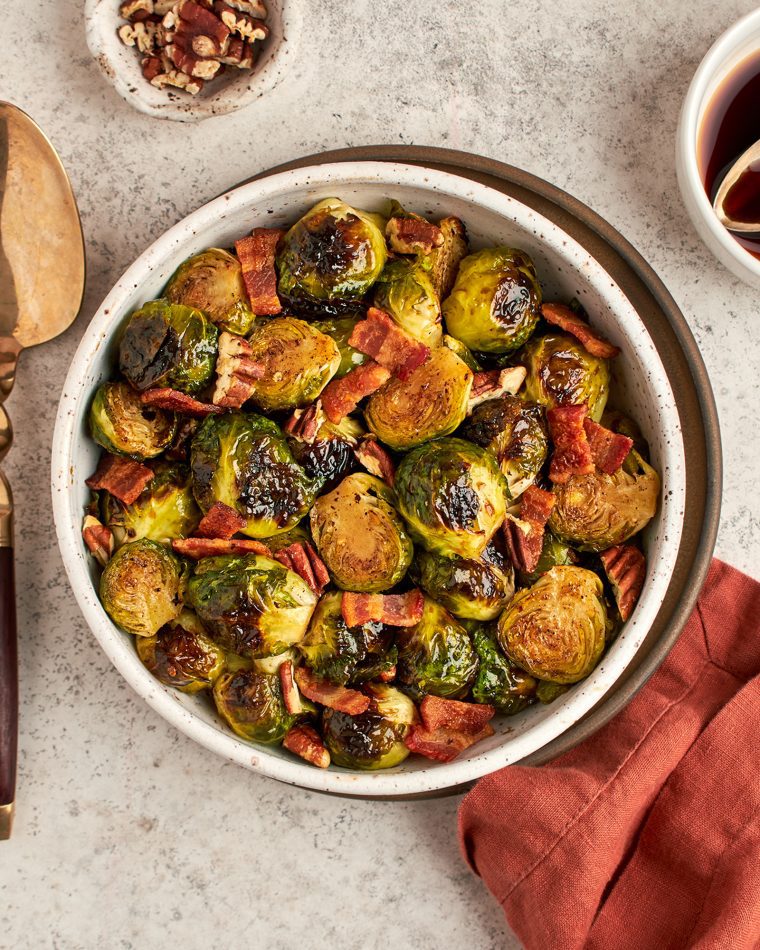 roasted Brussels sprouts with bacon in bowl with serving spoon and linen napkin