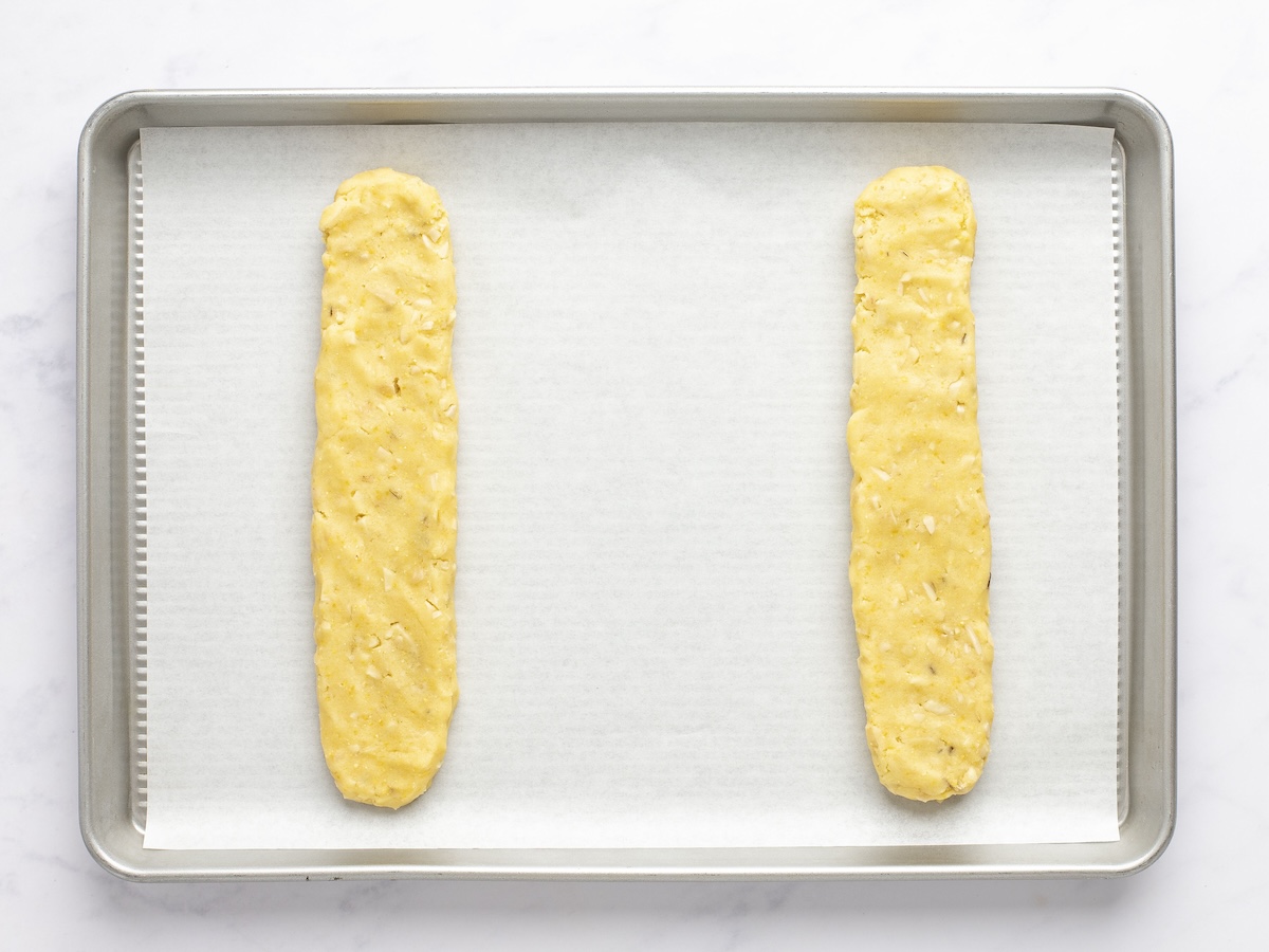 Biscotti dough logs formed on parchment-lined baking sheet.