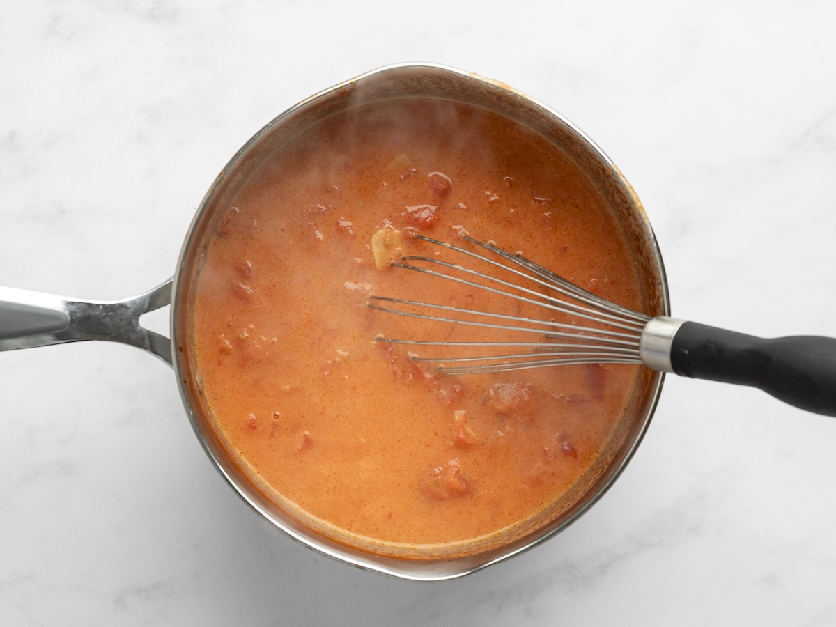 whisking creamy tomato sauce.