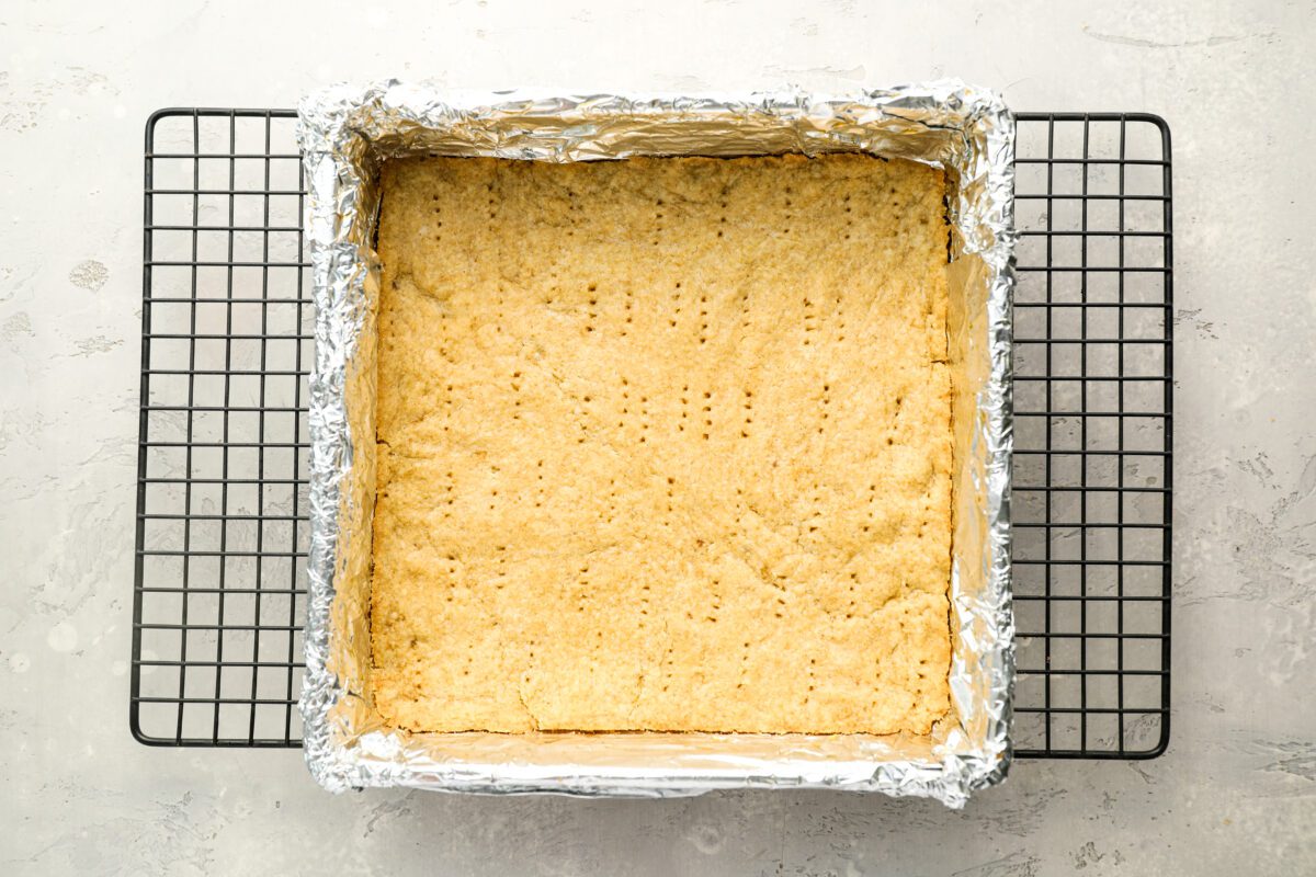 baked docked millionaire's shortbread crust in foil-lined baking pan, cooling on rack.