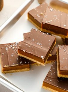 millionaire's shortbread bars on baking sheet with bowl of flaky sea salt.