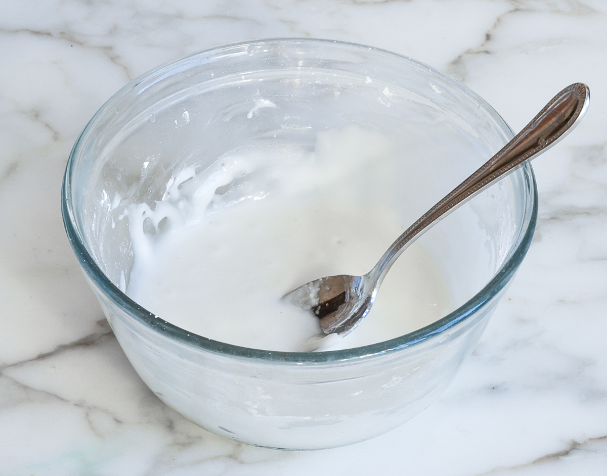 glaze for lemon pound cake in mixing bowl with spoon.